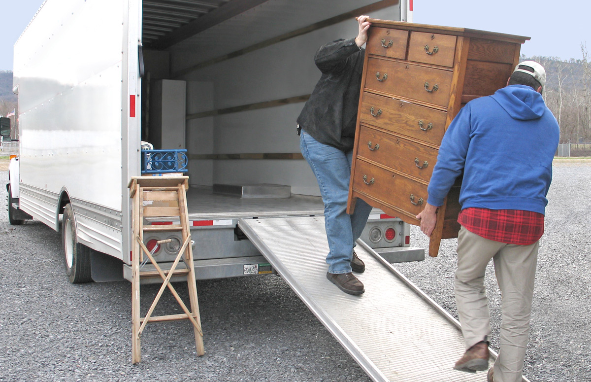 Deux personnes chargent une commode dans un camion de déménagement. On déménage léger... en carbone!
